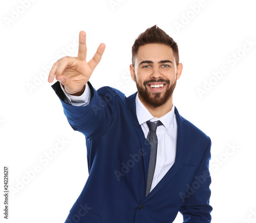 Happy young businessman showing victory gesture on white background