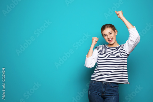 Happy young woman celebrating victory on color background. Space for text