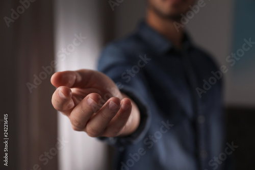 Man offering helping hand on blurred background, closeup