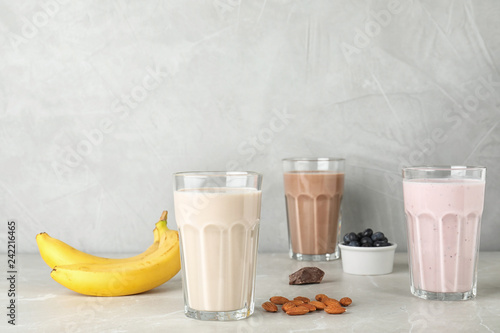 Glasses with different protein shakes and ingredients on table. Space for text