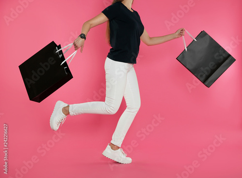 Woman running with paper shopping bags on color background. Mock up for design