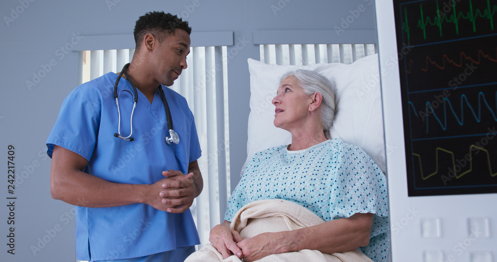 © rocketclips - Sick senior woman resting in hospital bed after surgery talking to young male nurse. Portrait of african-american nurse assisting ill female patient lying in bed © rocketclips - Sick senior woman resting in hospital bed after surgery talking to young male nurse. Portrait of african-american nurse assisting ill female patient lying in bed