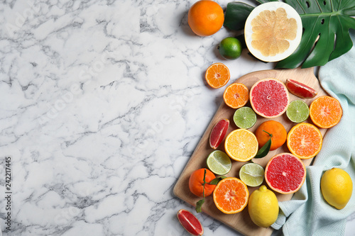 Different citrus fruits on marble background  top view. Space for text