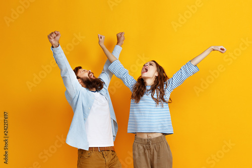 young happy couple won emotionally celebrating win on colored yellow background photo