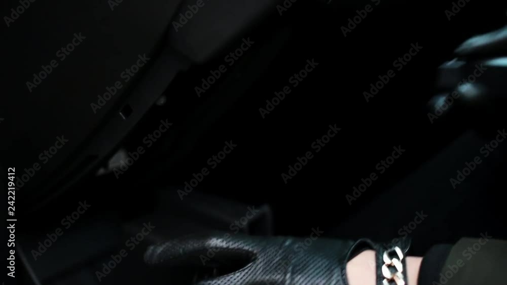 Hands wearing black leather gloves and bracelet open car glove box and put some plastic electronic square shaped device with red blinking lamp inside of car. Hands wearing black leather gloves and bracelet open car glove box and put some plastic electronic square shaped device with red blinking lamp inside of car.