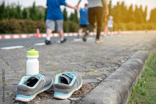 Select focus shoses and water bottles., People are walking  for their good health in the public park background, sunset on evening. - Image photo