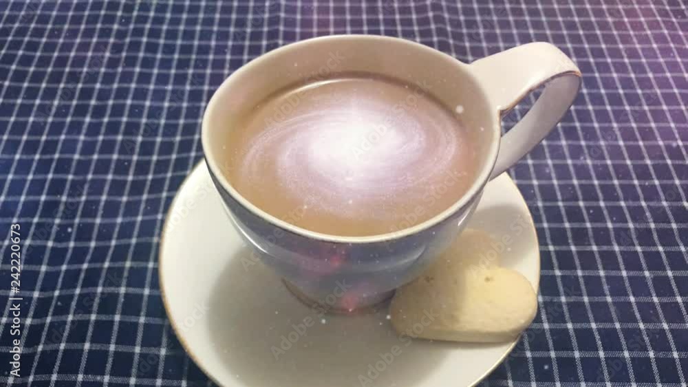 Cinemagraph - Galaxy in the cup of coffee. Steaming white cup of coffee with rotating galaxy in it on a table with a checkered tablecloth Cinemagraph - Galaxy in the cup of coffee. Steaming white cup of coffee with rotating galaxy in it on a table with a checkered tablecloth
