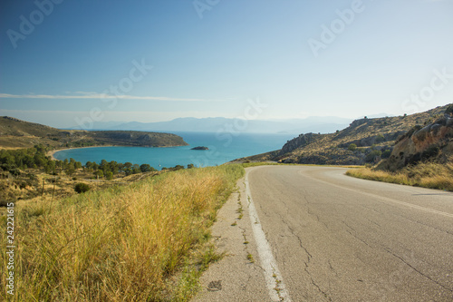 empty curved old car road in dry summer yellow highland nature environment landscape with sea bay background view