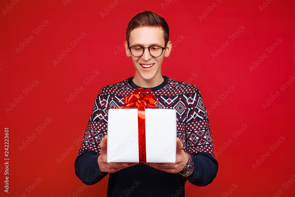 Portrait of a man with glasses, with a gift box in hand, on a red background Portrait of a man with glasses, with a gift box in hand, on a red background