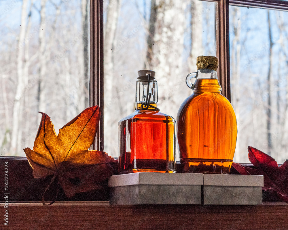 Foto Maple syrup in old bottles at window