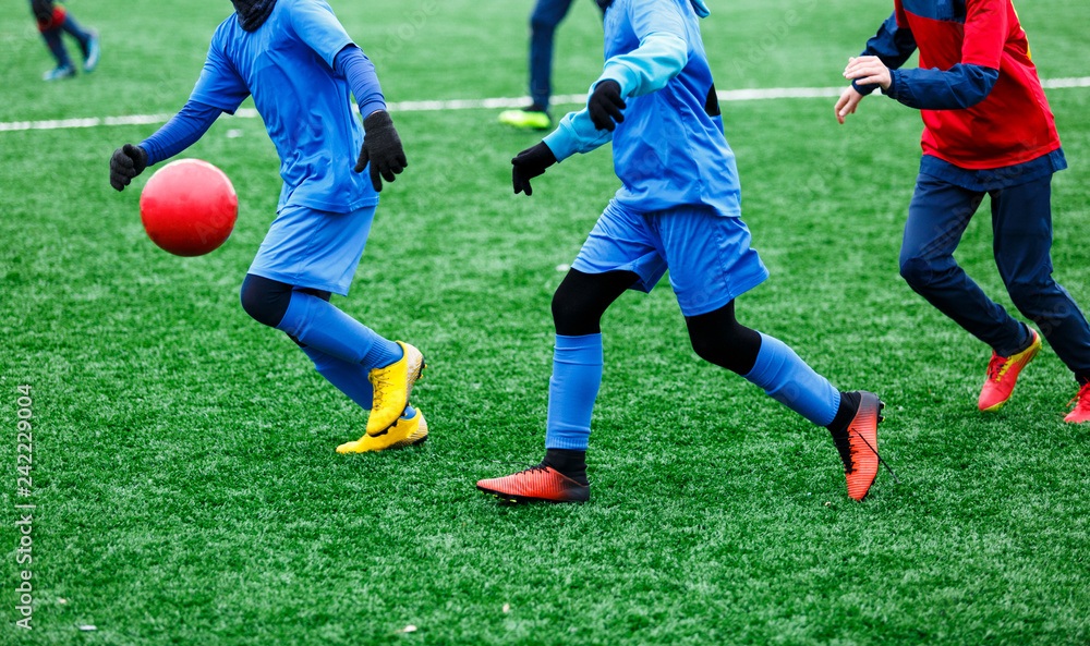 Two young Footballers in red and blue sportswear running,dribble and competing for ball. Junior football match competition. Winter activities, soccer game, training concept Two young Footballers in red and blue sportswear running,dribble and competing for ball. Junior football match competition. Winter activities, soccer game, training concept