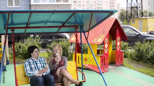 Young lovely couple at swings eating ice creama nd have fun at cloudy weather photo