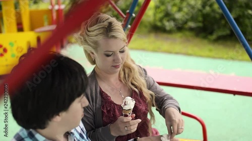 Young lovely couple at swings eating ice creama nd have fun at cloudy weather photo