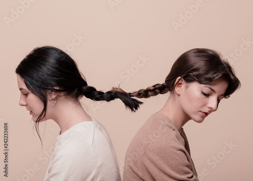 Studio shot of two young women with braids tied together
