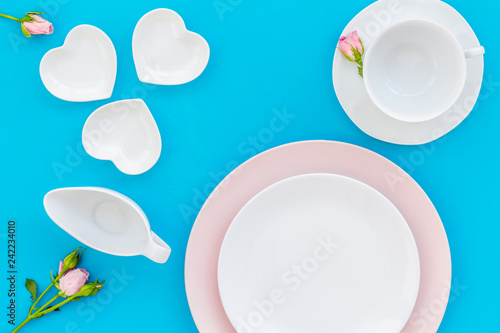 Empty white and pink colorful plate and rose for table setting on blue table backgroung top view copy space
