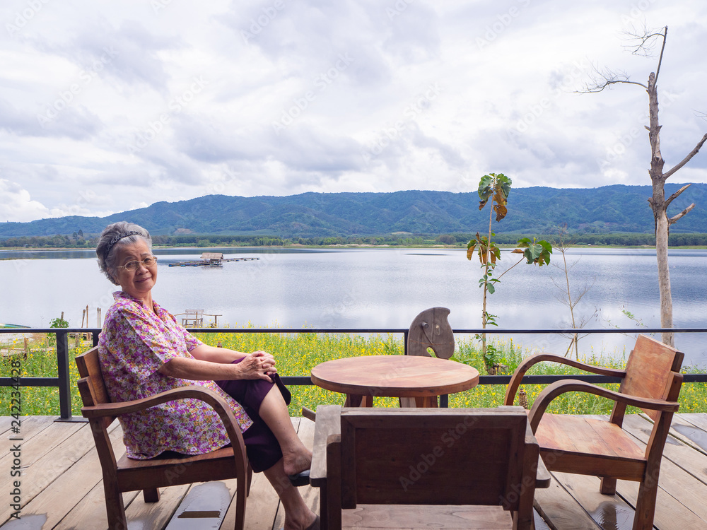 Portrait of elderly woman sitting side the lake.