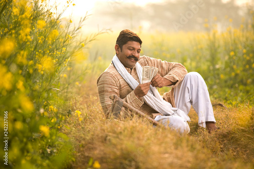 Farmer holding Indian Rupee notes in field