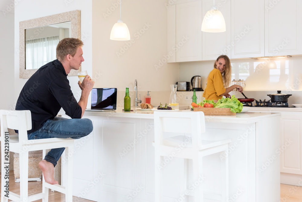 Couple cooking on a white kitchen at home Couple cooking on a white kitchen at home