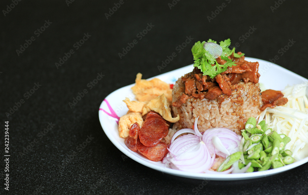 Fried rice Shrimp paste with pork and fried egg in plate on black table. Thai food (Kao Cluk Ka Pi). - obrazy, fototapety, plakaty 
