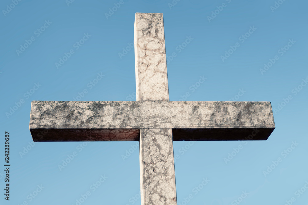 A big stone cross against a clean blue sky. Symbolic shape: christianity, religion, salvation.