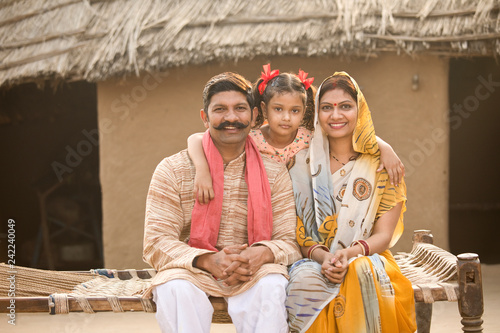 Indian family sitting on traditional bed in village