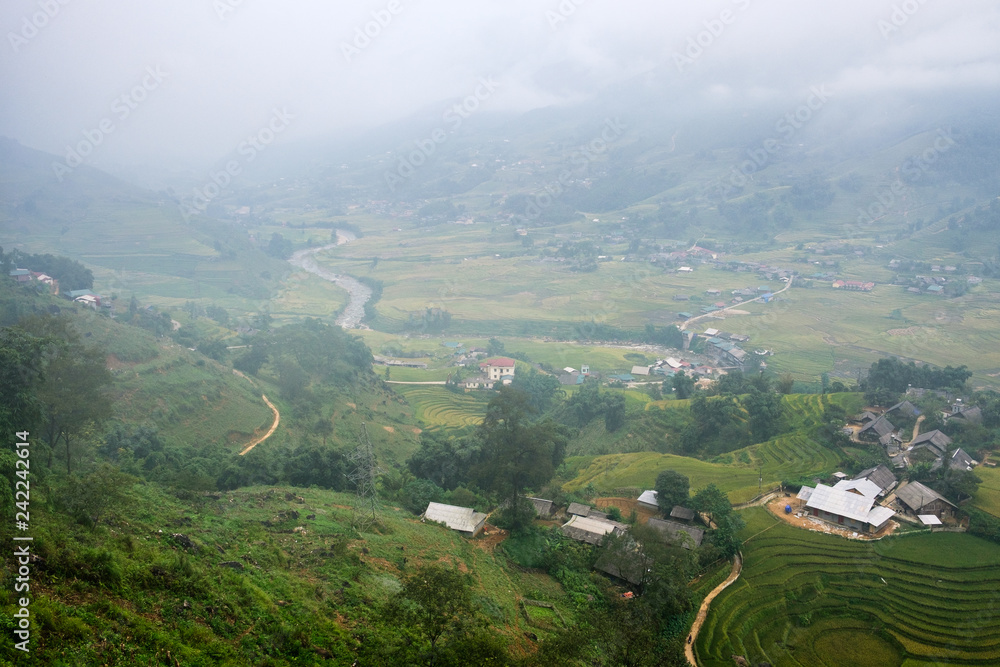 View of Tavan village on rice field terraced with river in foggy day at Sapa