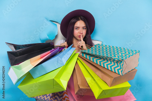 Canvas-taulu Shopping fashion young woman holding paper bags isolated on blue background with copyspace