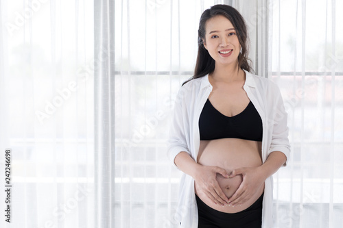 Free Download pregnant woman holding hands in heart shape on belly - GFXLoad