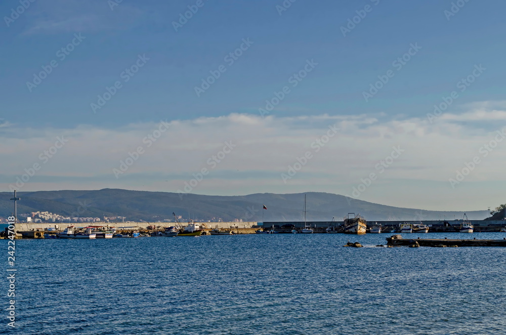 Seascape of pier with cross at end for fishing boat in the Black Sea and Balkan mountain with Cape Emine near ancient city Nessebar, Bulgaria, Europe