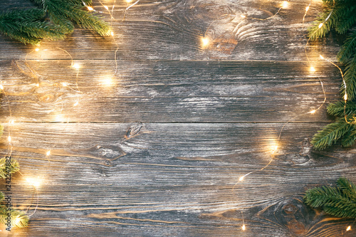 Fir branches and garland lights on wooden table. Christmas and New Year frame...