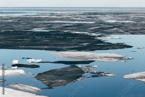 Принти на полотні Huge black ice floes on blue water surface. Spring background