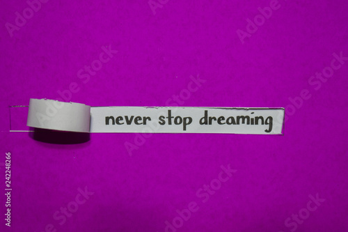 Never Stop Dreaming, Inspiration, Motivation and business concept on purple torn paper