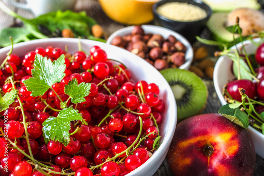 Red currant on table with food. Healthy super foods for breakfast, bowls with organic fresh fruits and nuts. Vegetarian diet concept. Red currant on table with food. Healthy super foods for breakfast, bowls with organic fresh fruits and nuts. Vegetarian diet concept.