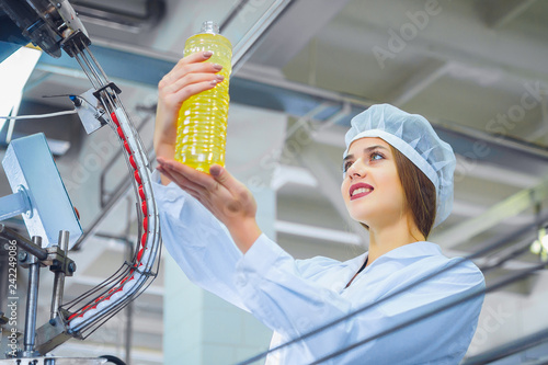 Young beautiful girl in white overalls at the plant for the production of sunflower and olive oil. Quality control in production