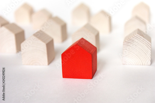 Rows of wooden houses with single red house in center on white background photo