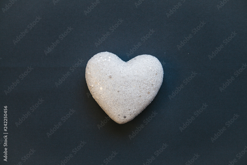 Obraz premium White heart on a dark background. Concept for Valentine's Day or Women's Day or the topic of health, life, donation and help. In minimal style.