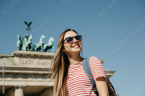 Canvas Print Portrait of a young beautiful positive smiling stylish tourist girl near the Brandenburg Gate in Berlin in Germany