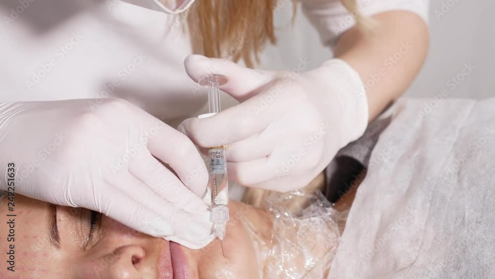 doctor beautician pricks the patient's face with a drug based on hyaluronic acid to tone the skin of a woman doctor beautician pricks the patient's face with a drug based on hyaluronic acid to tone the skin of a woman