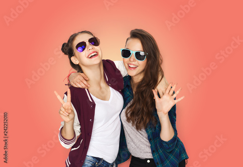 people  fashion and summer concept - happy smiling pretty teenage girls in sunglasses showing peace hand sign over living coral background