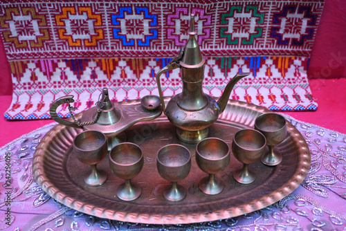 Traditional Palestinian tea set: made of bronze teapots, cups and tray – placed on a tablecloth.  photo