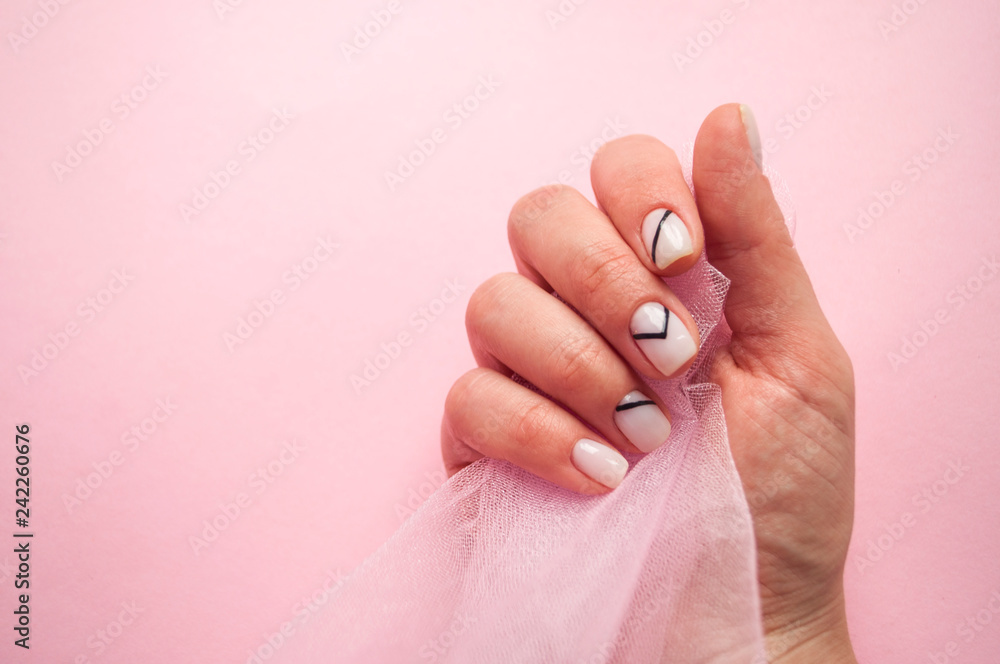 Young woman's hand with beautiful manicure on pink background holding a piece of tulle with copyspace. Young woman's hand with beautiful manicure on pink background holding a piece of tulle with copyspace.