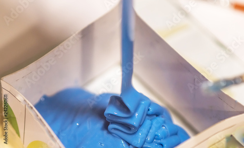 Process of putting blue liquid silicone rubber into mold form for making copies photo