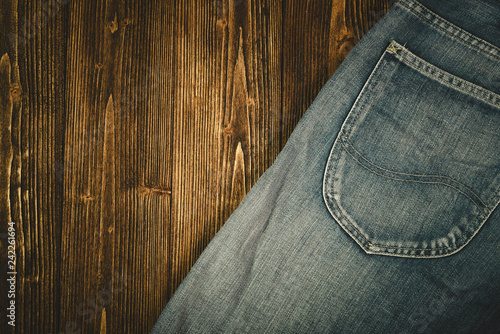 Frayed jeans or blue jeans denim collection on rough dark wooden table background, top view with copy space, old fashion concept.