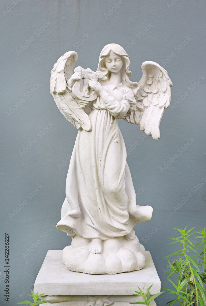 Beautiful angel statue against gray wall background.