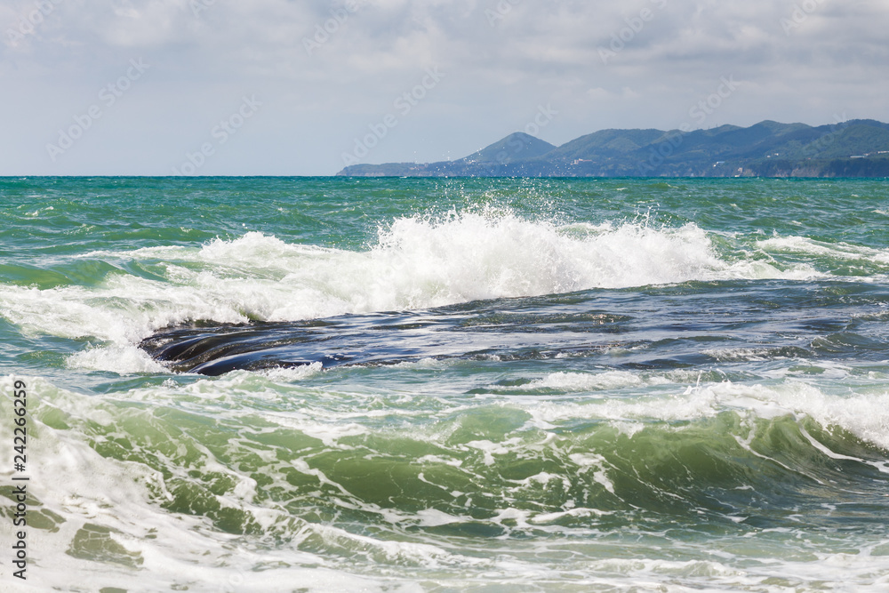 Waves in turquoise sea crashes over rocky coast at warm sunny day. Tuapse, Russia Waves in turquoise sea crashes over rocky coast at warm sunny day. Tuapse, Russia