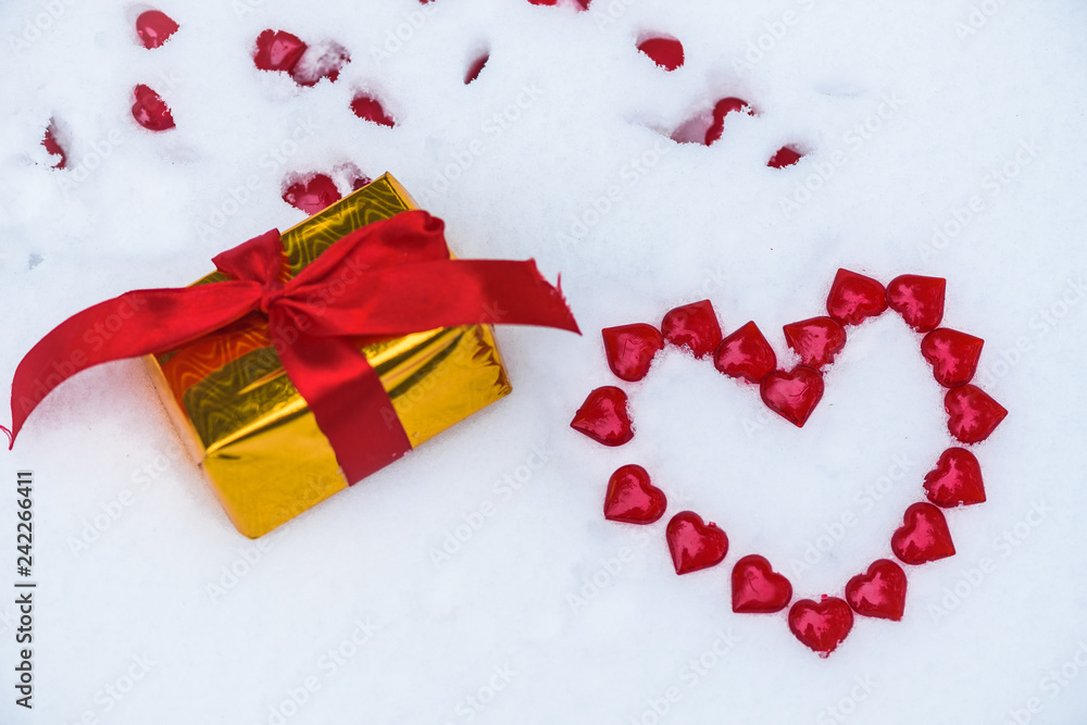 the figure of a heart laid out on the snow of little red hearts on the snow on Valentine's Day .a surprise gift around. background image the figure of a heart laid out on the snow of little red hearts on the snow on Valentine's Day .a surprise gift around. background image