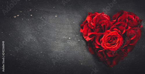 Heart-shaped red roses on stone background.