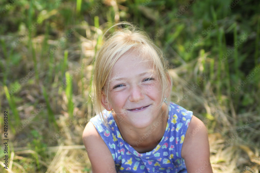 Portrait of a little smiling girl. Summer smile. Summer moments. Little girl in the grass. Portrait of a little smiling girl. Summer smile. Summer moments. Little girl in the grass.