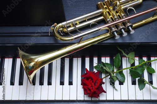 Piano keyboard, trumpet and red rose. Close-up photo