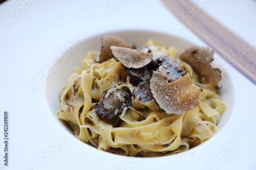 pasta with black truffles on wood background , Italian food photo